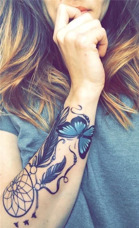 grafisk drömfångsttatuering., bågnät och svarta fjädrar och fjärilsritning i svart och blått, kvinnearm