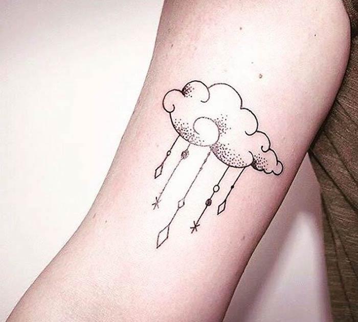 Muž s tetovaním na predlaktí a tetovaním s malými mrakmi