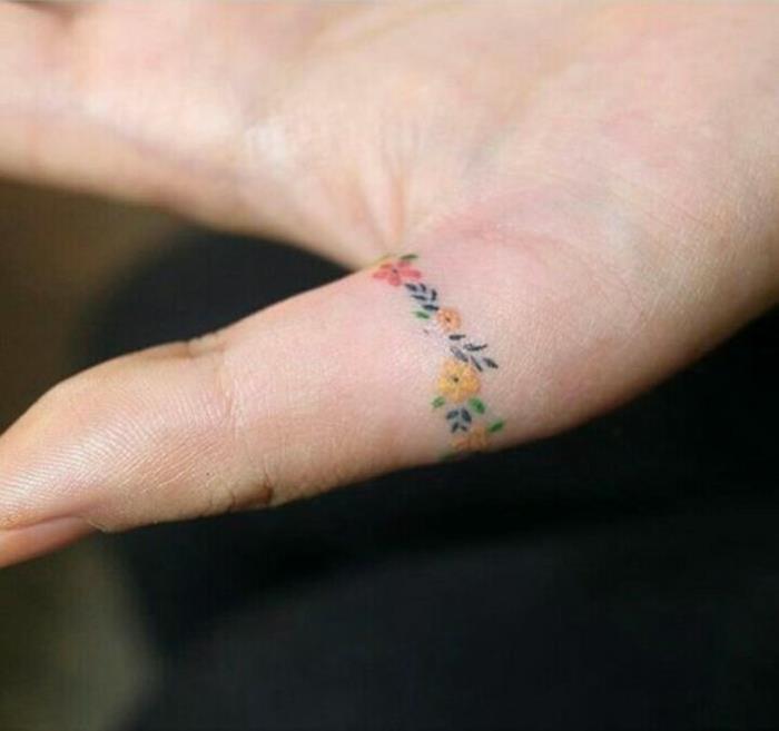 en tatuering på fingret i minimalistisk anda, färgglada blomstertatueringar