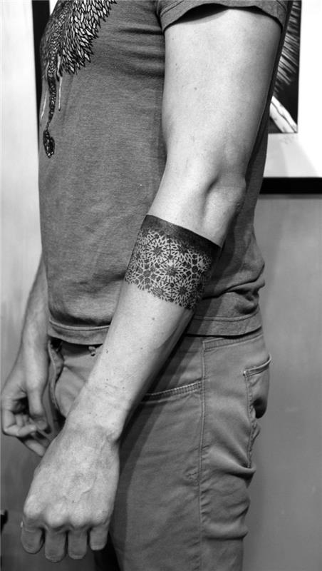 geometrické tetovanie na rukáve s originálnym dizajnom, ktoré hrá v kontraste medzi čiernym pásom a rozetovými vzormi
