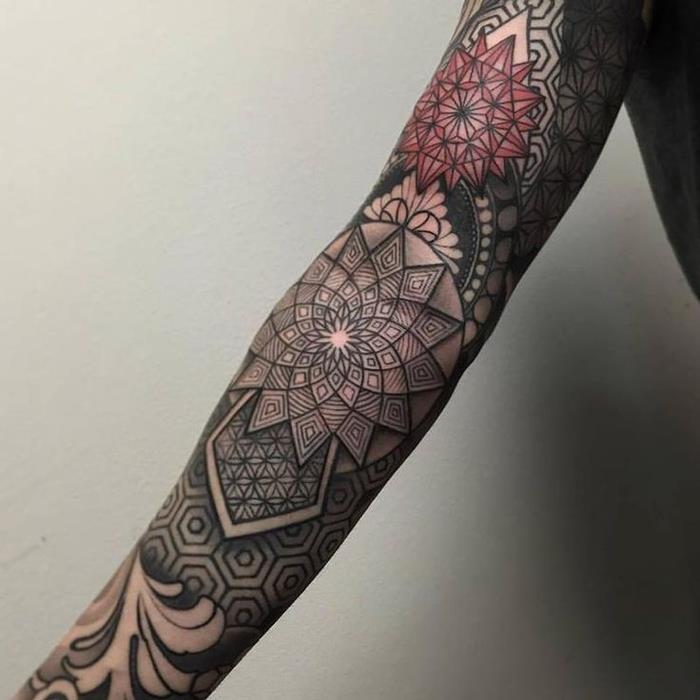 mužské tetovanie na celú pažu zložitej ornamentálnej kompozície geometrických tvarov a symbolov
