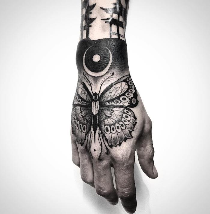 motýľové tetovanie, silueta motýľa s kmeňovými vzormi na ruke, celkom nápad na čierne tetovanie