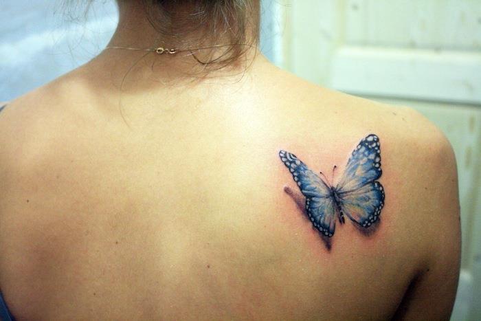 3D tetovanie motýľa, zlatý náhrdelník, zopnuté hnedé vlasy, vzor modrého motýľa