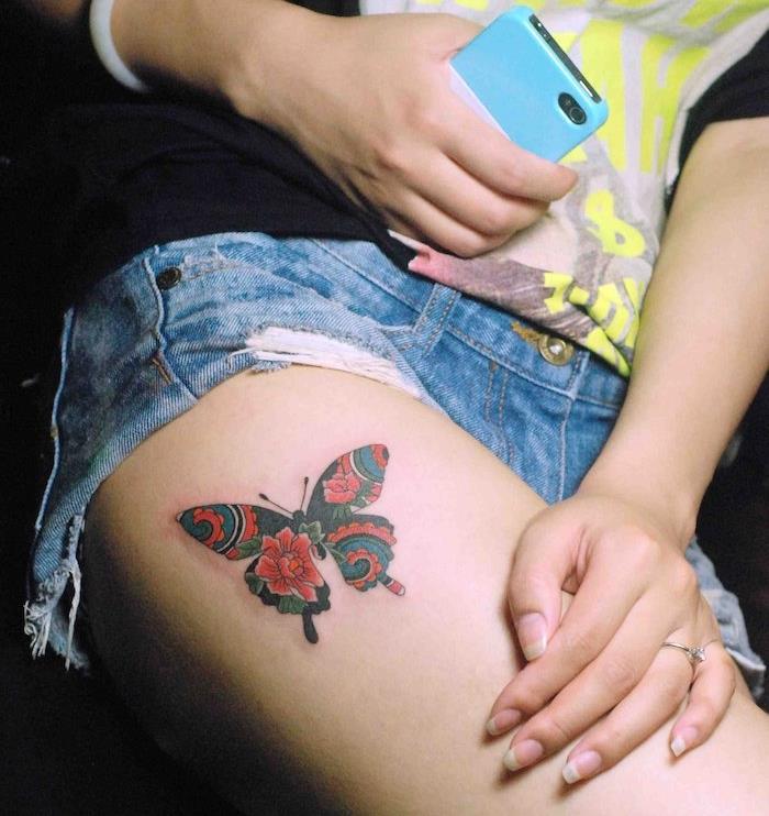 symbolické tetovanie, džínsové rifle s čiernym tričkom, ženský prsteň s kryštálom, tetovanie motýľov v červenej a čiernej farbe