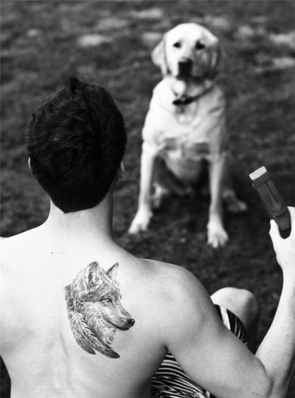 symbol tetovania, muž kráčajúci so svojim psom, tetovanie vlčej hlavy na chrbte