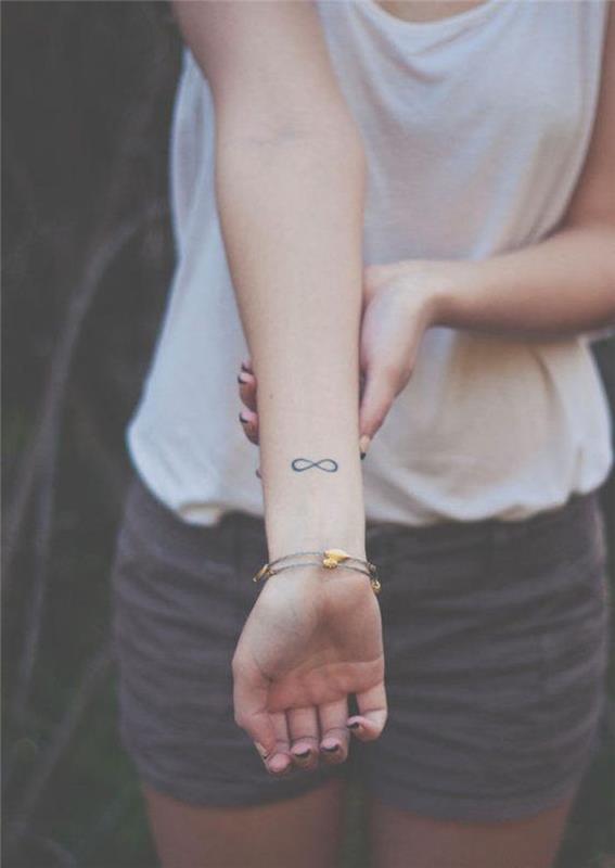 liten diskret infinity -tatuering på kvinnans handled