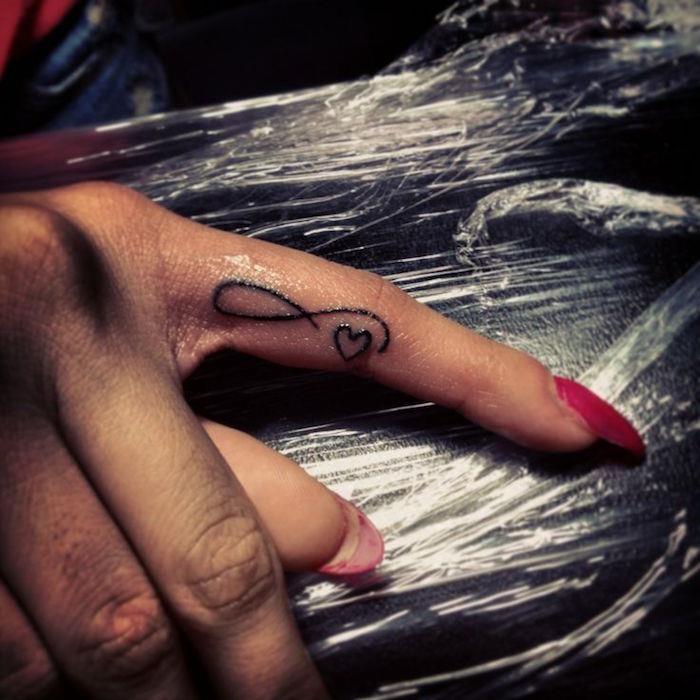 nekonečné tetovanie a malé srdiečko na prste ako modelové tetovacie prsty žena