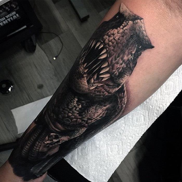 Tattoo uomo braccio con il disegno di un dinosauro con la bocca aperta