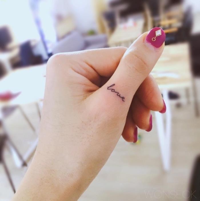 Scritta love in inglese, tatuaggio sul dito, manikure con brillini
