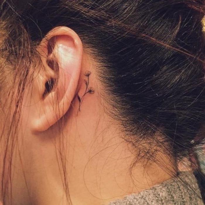 Tatuaggio dietro l'orecchio, tattoo disegno fiore, donna con capelli legati