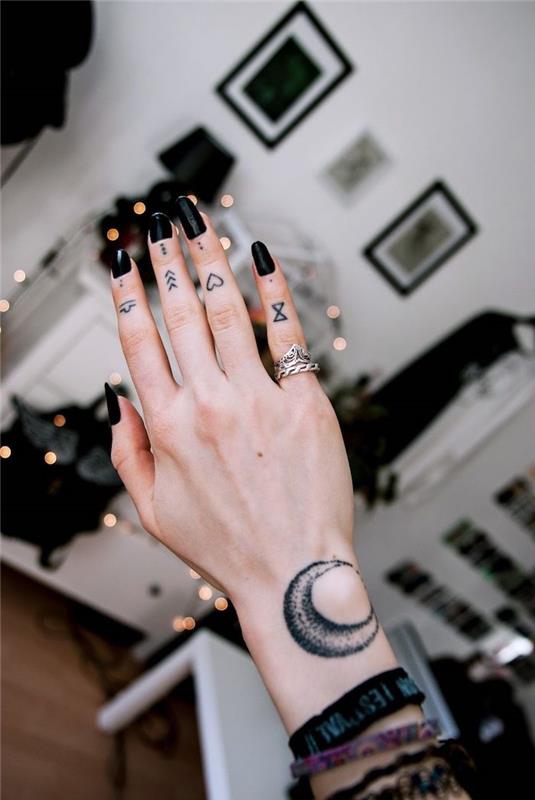 Tatuaggio sul dito di una donna con tanti simboli di frecce e cuori