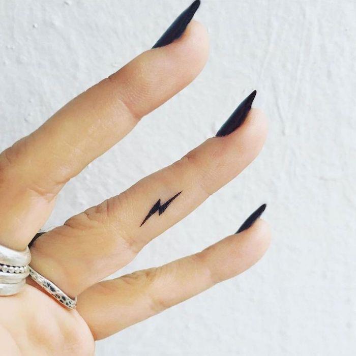 Mani tatuate e un'idea con un un piccolo fulmine sul dito anulare di una donna