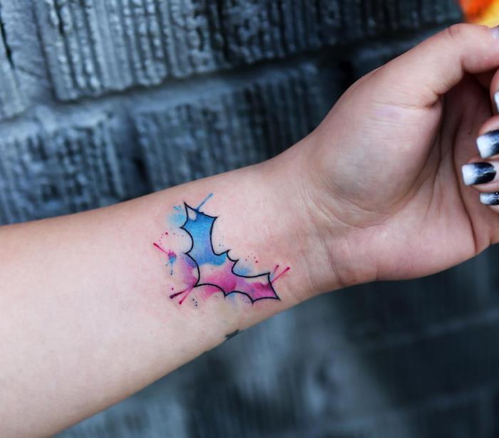 Il polso di una donna con tatuaggio di un pipistrello colorato