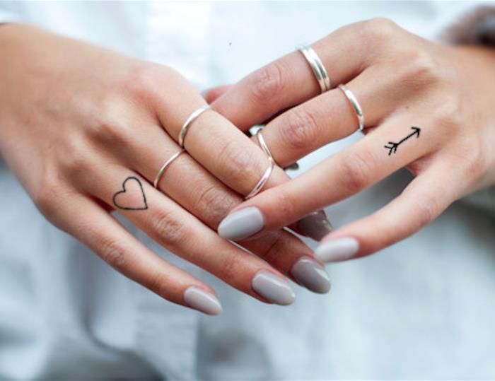 وشم الحروف ، un'idea con due tatuaggi cuore e freccia sulle dita delle mani di una donna