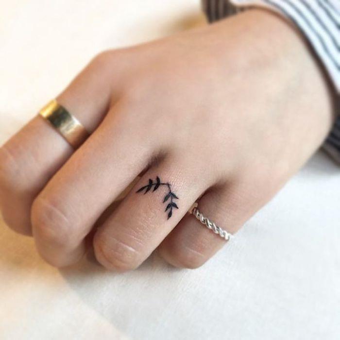 La mano di una donna con un piccolo tattoo floreale sul dito anulare