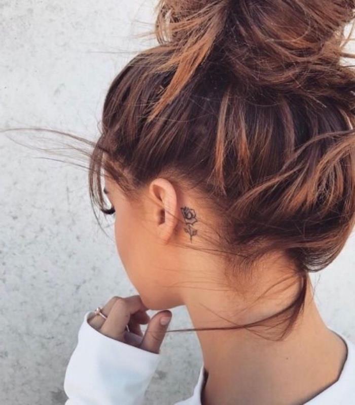 Ragazza con capelli castani, tatuaggi femminili eleganti, capelli legati a chignon