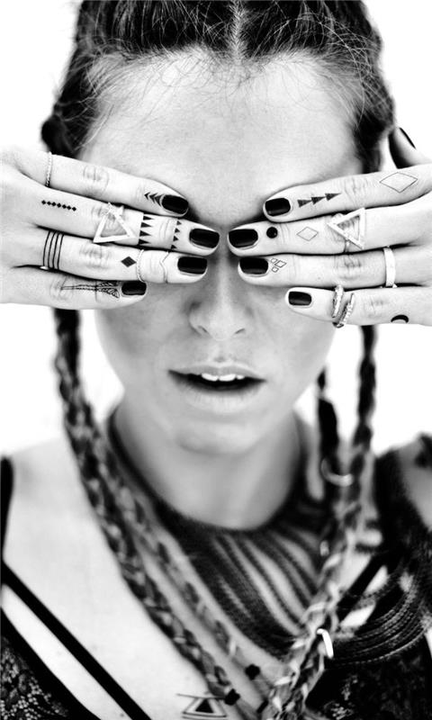 Idea per dei tatuaggi sulle mani ، الوشم con simboli triangoli e linee sulle dita di una donna