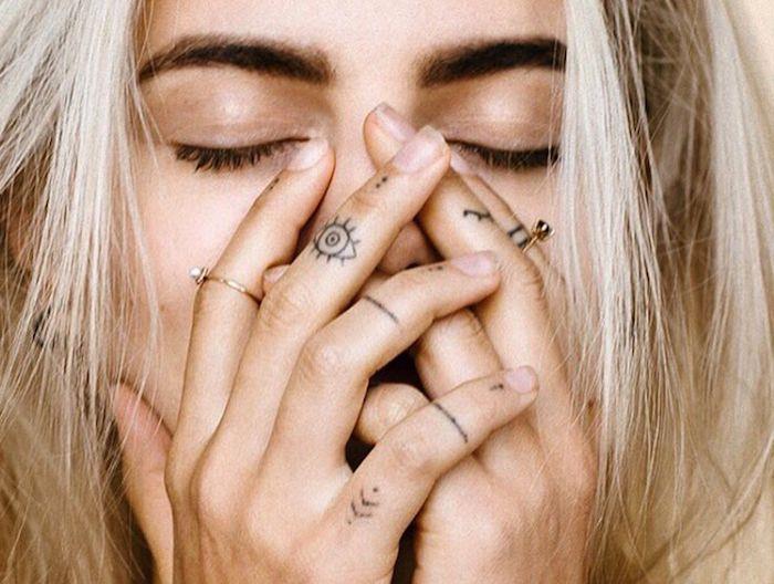 Tatuaggi sulle dita di una donna con simbolo occhio e frecce