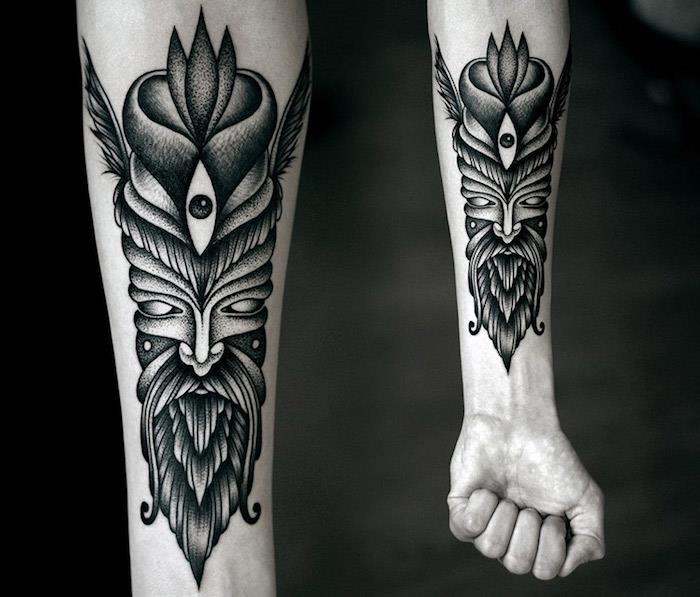 Tatuaggi uomo e il disegno di una maschera tribale sull'avambraccio