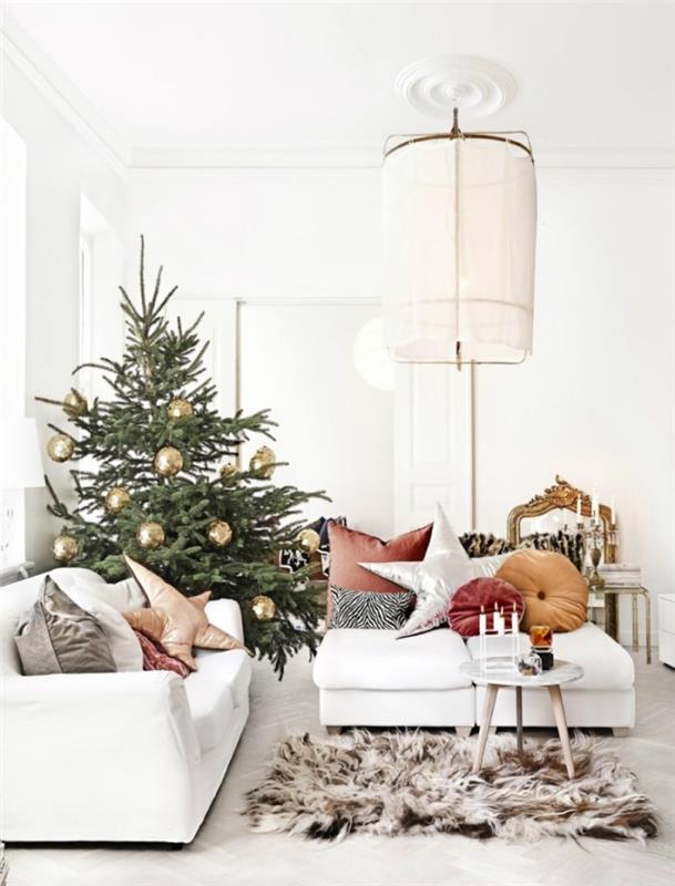 bild av naturlig julgran dekorerad med guldbollar i ett vitt rum möblerat med vita möbler