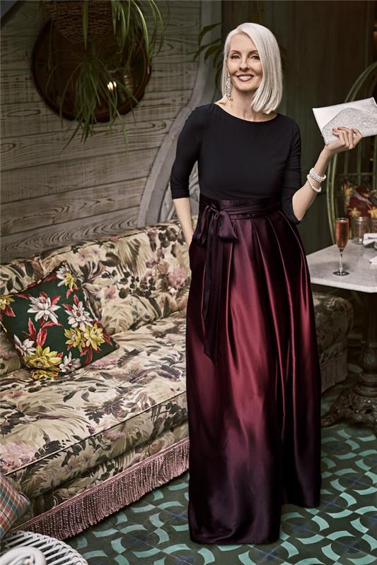 60 -årig kvinna bröllopsklänning med vinröd lång kjol och svart topp med långa ärmar 50 år gammalt kvinnomode