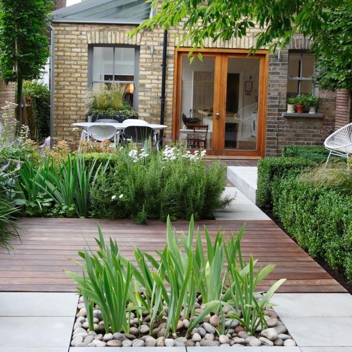 moderný vonkajší dizajn s dlaždicovou a drevenou terasou, malou zenovou záhradnou výzdobou s kamienkami a zelenými rastlinami