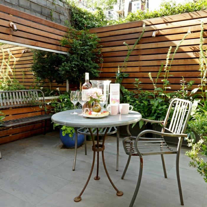 Zen -terrass, träskiva och betongplattor, bord, metallstol och bänk, flera växter, rektangulär spegel