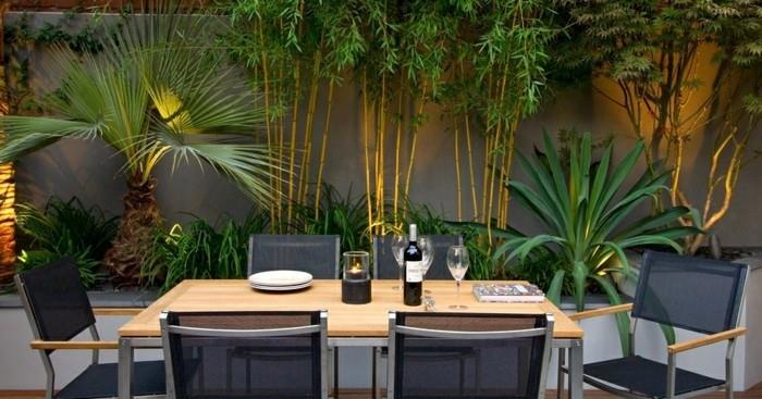 Zen terrass layout med utomhus matplats, träbord, svarta stolar, bambu och gröna buskar