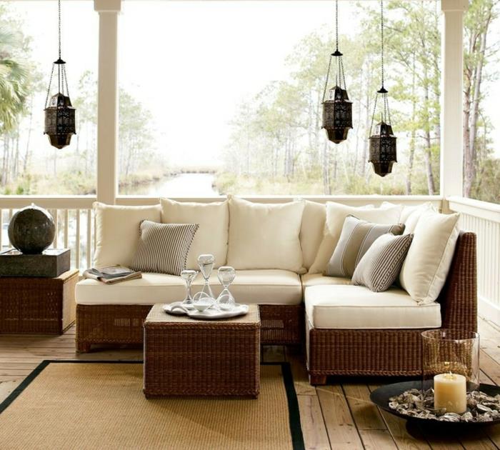 flätad trädgårdsmöbelidé, rottingsoffa och bord, vitt säte och dekorativa kuddar, orientaliska upphängningar, dekorativt ljus