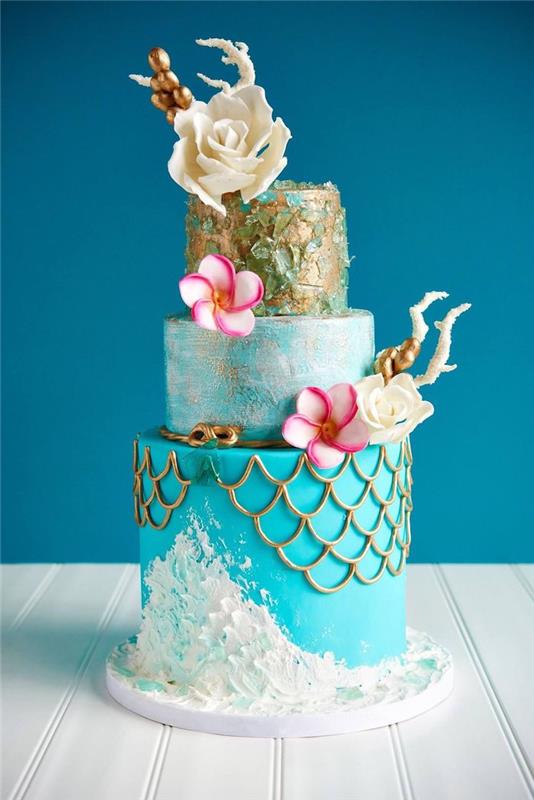 sjöjungfrun mönster tårta i vitt, blått och guld med vit choklad blomma dekoration och färska rosa och vita blommor