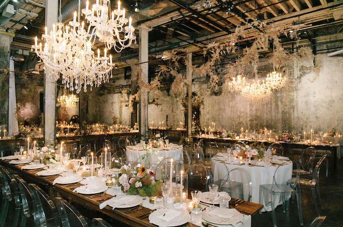industriálna svadobná výzdoba v svadobnej sieni s hrubými stenami, elegantnými lustrami, priehľadnými stoličkami okolo dreveného stolu