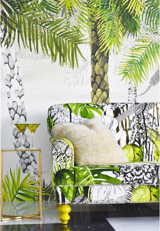 tropisk tapet, glas- och mässingsbord, vit fuskpälskudde, soffa i tropiskt mönster i vitt och grönt