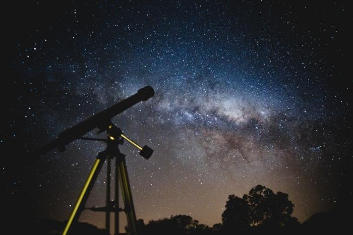 خلفية مراقبة الفضاء من التلسكوب في الطبيعة تحت سماء الليل المنقطة بالنجوم