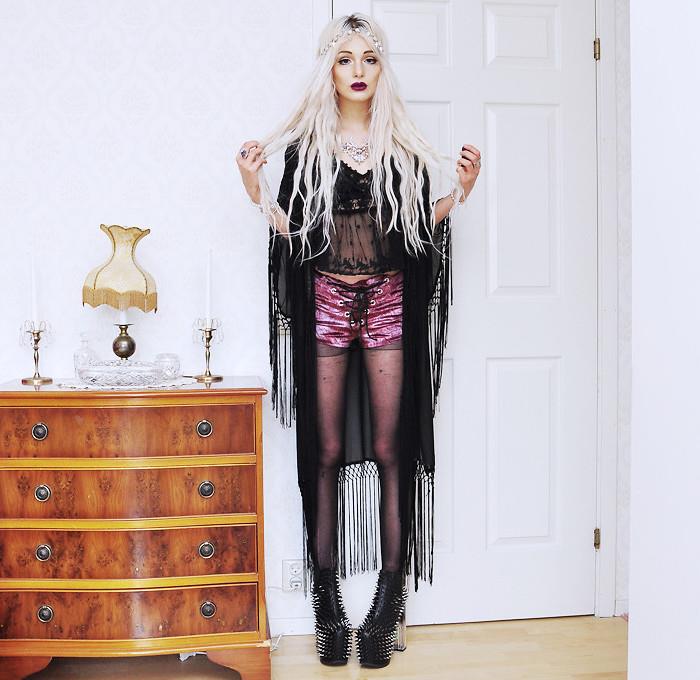 hemlagad halloweenkostym, polarblont hår med halsband, transparent svart topp och rosa shorts, dubbade stövlar, svart eyeliner -smink och rött läppstift