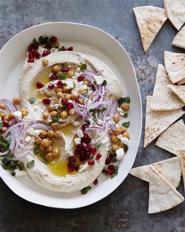 vegetariskt recept på superskål, hummus med kikärter, lök och granatäpple, i en vit tallrik
