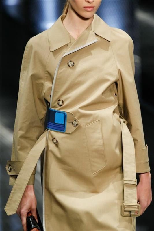 kvinna-trench-coat-med-dekorativa-element-i-blå