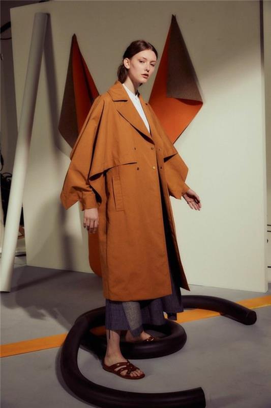 kvinna-i-orange-fladdermus-stil-trench-coat