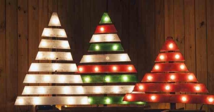 Vianočné stromčeky v paletách namaľované bielou zelenou a červenou farbou a osvetlené malými lampami