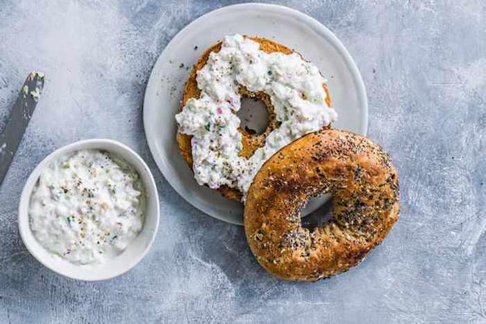 rožok nakrájaný na polovicu podávaný s gréckym tzatziki šalátom z jogurtu a kyslej uhorky