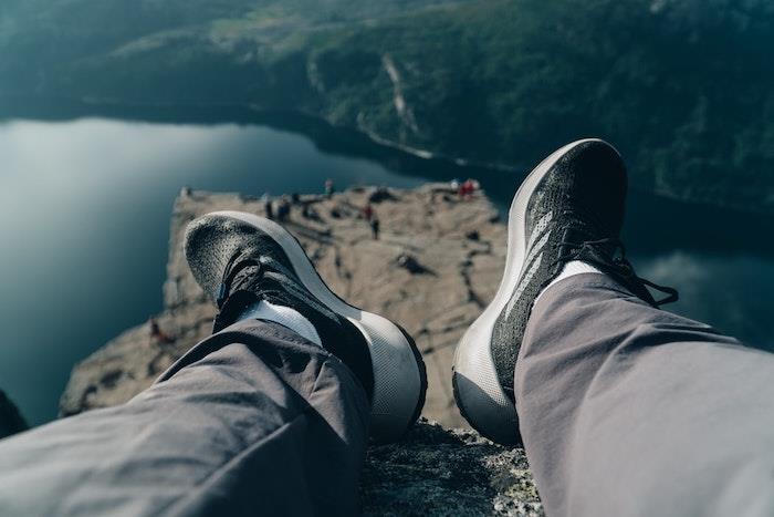 en man som sitter på en sten vilar och bär svarta sneakers