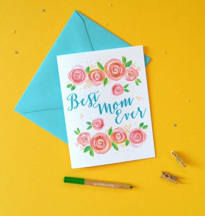 Deň matiek kvetinová karta s modrou obálkou a ceruzkou na žltom povrchu