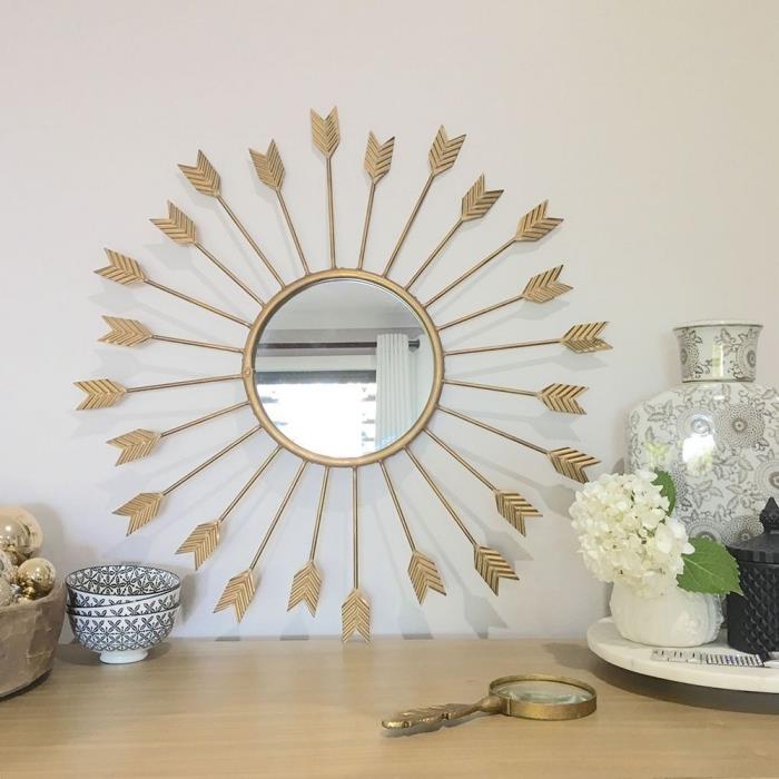 ديكور غرفة المعيشة الحديثة بجدران بيضاء مع خزانة خشبية فاتحة وأشياء عرقية ، نموذج مرآة بيضاوية ذهبية