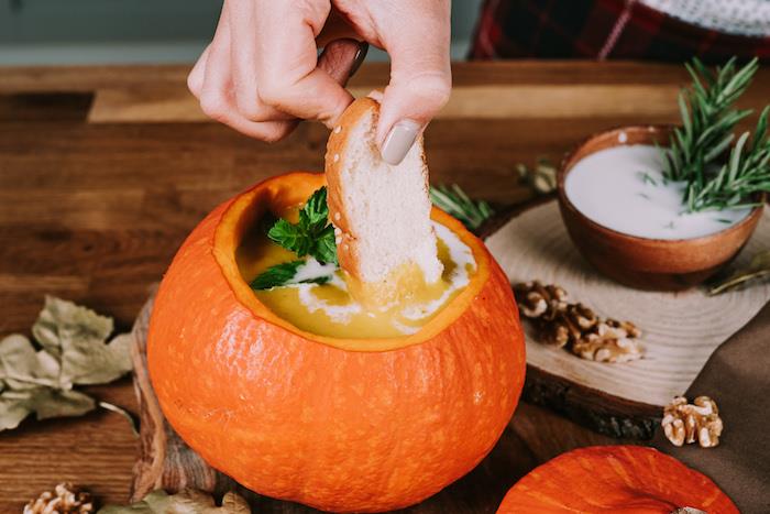 Inzuppare fetta di pane nella vellutata ، zuppe autunnali ، ciotola con latte di cocco e rosmarino