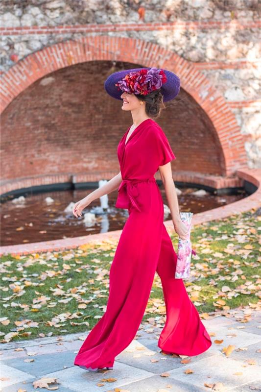 ako sa obliecť na svadbu, červený kombinézový model s splývavými nohami s opaskom, účesom s čiapočkou a kvetom