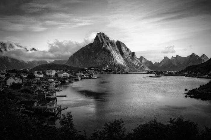 de vackraste landskapsbilderna i svartvitt, foto av en by vid en sjö skyddad från bergen någonstans i norge