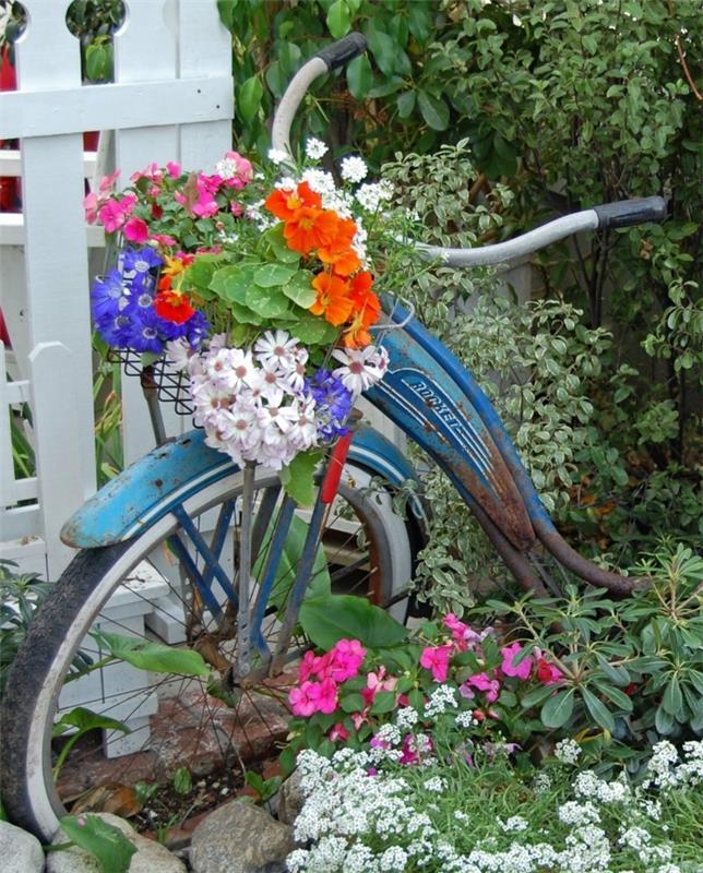 riklig grönska och blå cykel, blomkrukor på cykelkorg, dekoration av vintage blommaträdgård