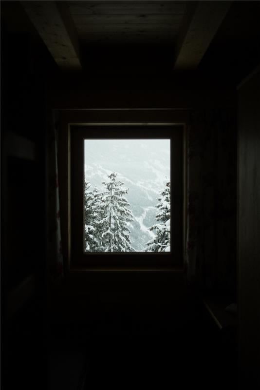 krásny nápad na vianočný obraz pre tapetu pre iphone, fotografia zasneženej krajiny s jedľami pred oknom spálne v podkroví