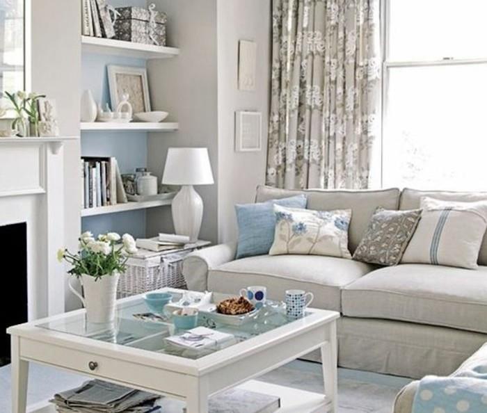 grå soffa, blå tryckta kuddar, grå färgscheman, glas soffbord, hängande hyllor