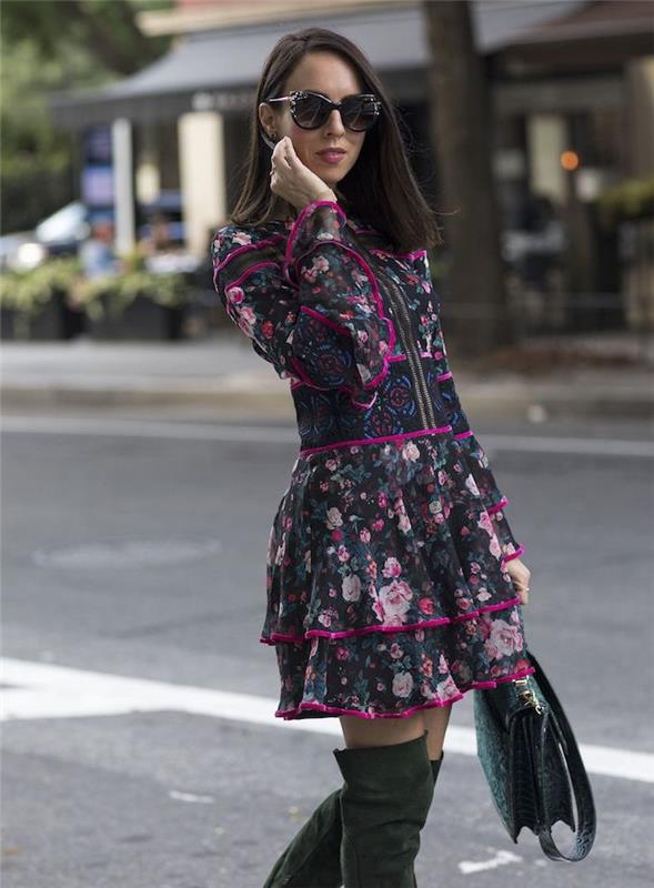 امرأة تمشي في الشارع ، ترتدي فستانًا بزخارف نباتية ، وحذاء يصل إلى الركبة ونظارة شمسية ، واتجاهات الموضة