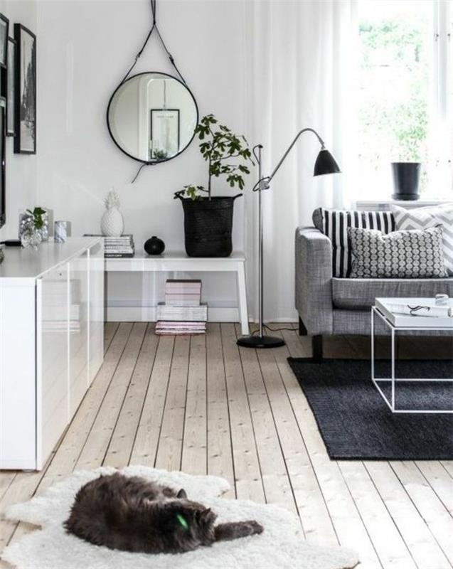 katt sover på en vit matta, fina vardagsrum, grå soffa, vit metall soffbord, trägolv